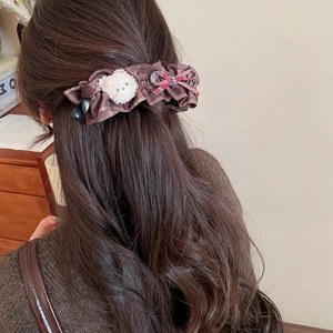 Détail d'une pince à cheveux avec ours en peluche et nœud à carreaux sur cheveux longs
