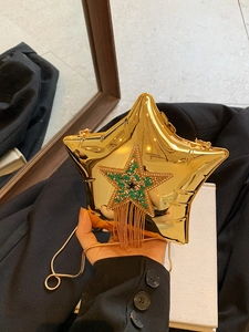 Detail of star-shaped gold crossbody bag with green crystals and metallic tassels