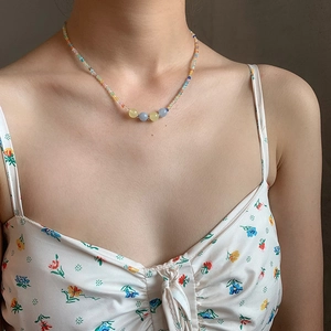 Close-up of a colorful beaded collar necklace with pastel round stones on a female model