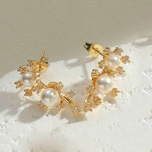 Detailed close-up of gold flower earrings with white pearls and sparkling cubic zirconia