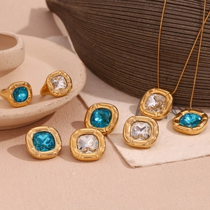 Macro view of gold-plated jewelry set with cushion-cut blue gems and clear zircons