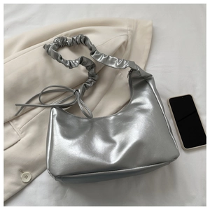 Detail der silbernen Metallic-Hobo-Tasche mit geriffeltem Gurt und Schleife