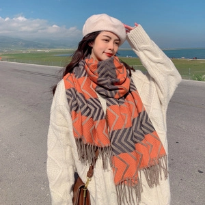 Detail of soft orange and grey plaid scarf with tassels worn in a scenic outdoor setting