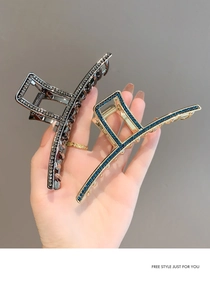 Close-up of luxury metal hair claws in black and gold with sparkling blue rhinestones