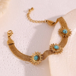 Macro shot of gold-plated woven mesh bracelet featuring blue turquoise sunflower charms