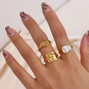 Macro of gold heart ring with 111 engraving and large emerald-cut zircon on fingers