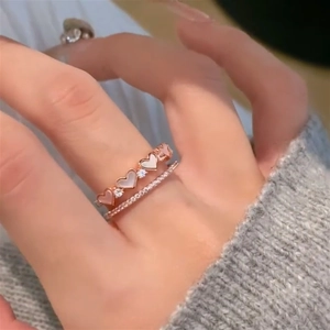 Detail of rose gold heart ring set with mother of pearl and zircon stones on hand