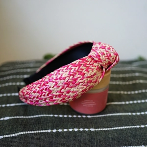 Detailed close-up of woven pink and beige raffia headband with central knot design