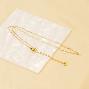 Elegant gold necklace with three teardrop zircon pendants on a white marble surface