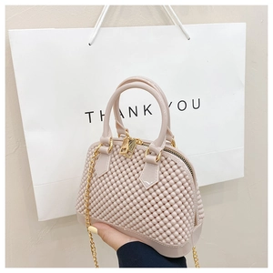 Close-up of beige PVC jelly shell bag featuring beaded texture and gold chain strap