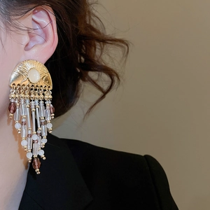 Macro view of vintage golden pearl tassel earrings with opal details on a model