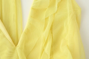 Close-up of bright yellow mesh fabric featuring ruffled layers and textured pleated details