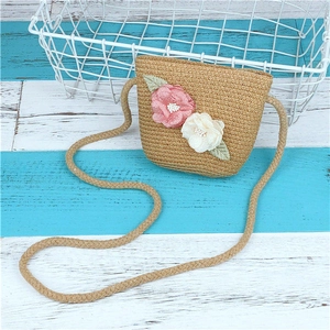 Détail d'un sac en paille avec des fleurs en tissu 3D faites main et des feuilles rustiques