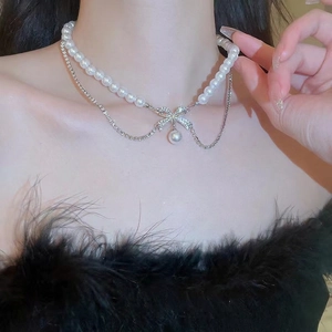 Double-layer pearl necklace with a sparkling diamond bow pendant on a female model