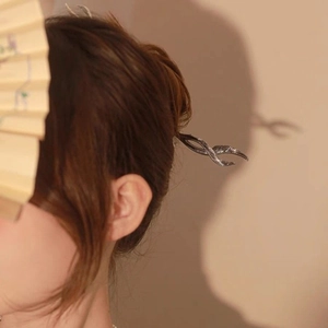 Detail of silver butterfly hair pin styled in a bun against a minimalist background
