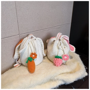 Detail of handmade crochet bucket bags with cute carrot and strawberry charms on plush mat