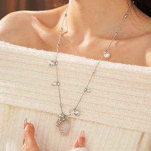 Close-up of elegant strawberry pendant necklace with pearls on a soft white sweater