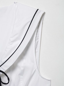 Detail of the high-quality stitching and black contrast trim on white sleeveless top