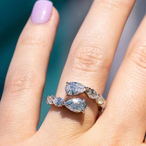 Macro detail of a bypass pear-cut ring featuring pavé set diamonds on a silver band