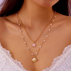 Detail of bohemian gold layered necklace with starfish pendant, shell, and white pearls