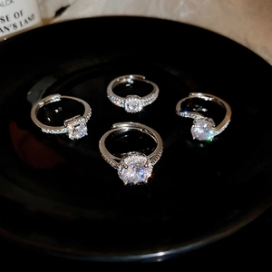 Macro shot of silver zircon rings with round and square stones on a black display base