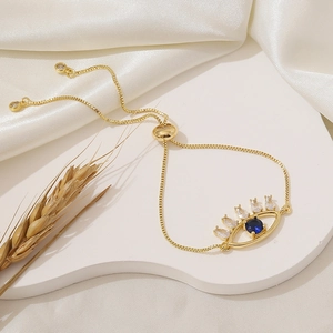 Detail of gold adjustable evil eye bracelet with blue and white cubic zirconia stones