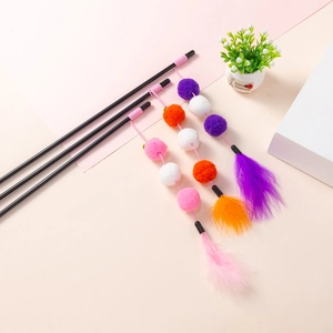Three cat teaser wands with colorful pom-poms, bells and feathers on a cozy background