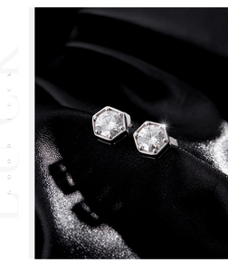 Macro view of sterling silver hexagonal moissanite stud earrings on black velvet