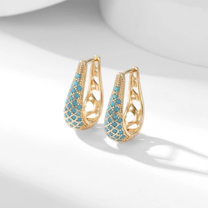 Detail of gold hoop earrings with turquoise beads and cutout heart patterns