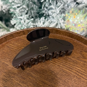 Detail view of coffee acetate hair claw clip on wooden tray with festive background