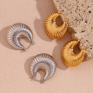 Detailed close-up of textured C-shape hoop earrings in polished gold and silver finishes