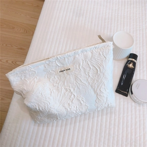 Detail of white 3D floral embossed canvas makeup bag with Simple Wish label and zipper