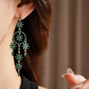 Side view of model wearing silver flower tassel earrings with green gemstones