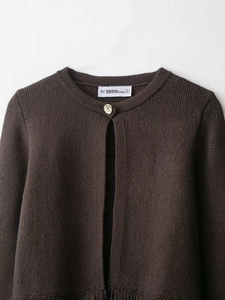 Détail d'un cardigan marron en maille avec col rond et bouton doré à texture gaufrée