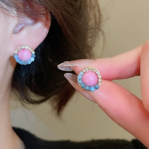 Close-up of pink crystal flower earrings with blue accent stones on a model