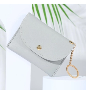 Detail of grey lychee textured leather coin purse with golden clasp and keychain chain