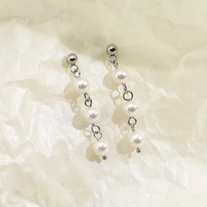 Détail de boucles d'oreilles en perles d'eau douce blanches avec perles en acier argenté