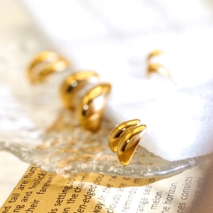Macro shot of gold teardrop earrings on ice-cracked glass with vintage newspaper background