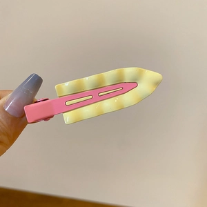 Detail of pink metal hair clip with yellow wavy pattern for women's hair styling