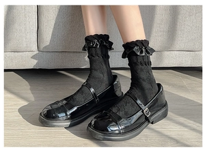 Close-up of black Lolita socks with ribbon lace trim and black patent leather shoes
