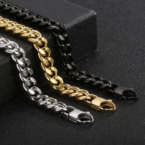 Close-up of polished stainless steel Cuban link chains in silver, gold, and black colors
