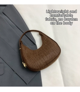 Detail of crocodile embossed leather texture and gold zipper on brown crescent bag