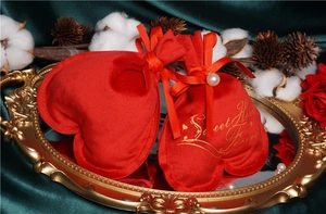 Detail of red heart-shaped velvet drawstring gift bag with golden Sweet Heart text
