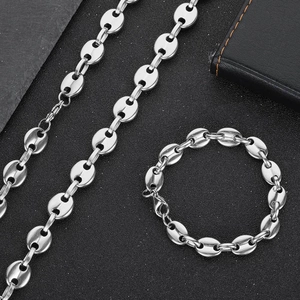 Flat lay of silver coffee bean chain necklace and bracelet set on black background