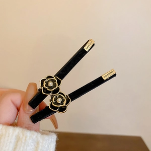 Set of two camellia flower hair clips with gold edging and white pearls on velvet