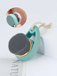 Detail of soft gray facial cleansing brush with teal handle and golden metal ring