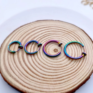 Macro shot of rainbow-colored stainless steel clip-on earrings in multiple sizes on wood