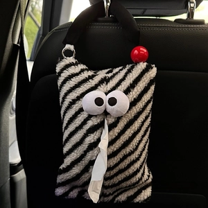 Plush monster car tissue holder with black and white stripes hanging on the seat back