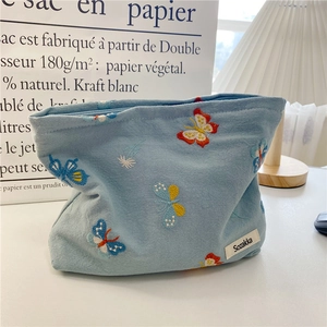 Detail of light blue cosmetic bag with butterfly embroidery and brand label