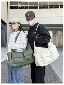Detailed view of canvas messenger bags in army green and off-white with large pockets